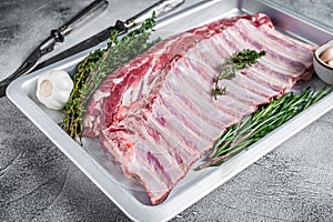Raw uncooked rack of mutton lamb ribs in baking dish. White background. Top view