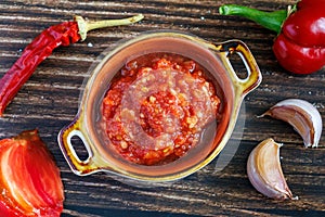 Raw uncooked Salsa or adjika sauce traditional Mexican or Caucasus Armenian sauce with tomatoes and hot chili peppers on photo