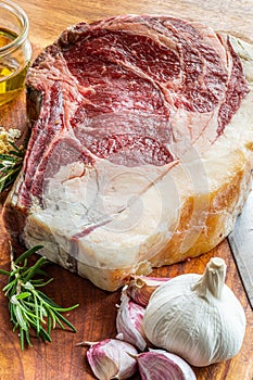 Raw vaca rubia gallega steak on wooden table with kitchen knife and seasonings