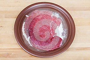 Raw veal schnitzel breaded in flour on plate