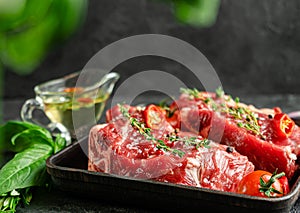 Raw veal steaks on grill pan with herbs and spicy oilive oil. Food preparation concept. Copy space photo