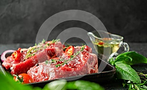 Raw veal steaks on grill pan with herbs and spicy oilive oil. Food preparation concept. Copy space photo