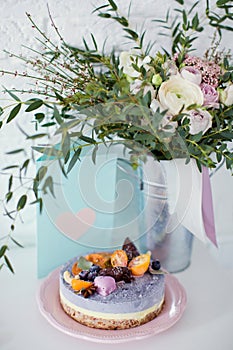 Raw vegan cake with fruits, seeds, chocolate and flower decoration