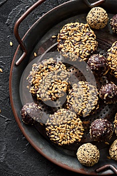 Raw vegan snack. Homemade energy bites and cookies with flax seeds in metal tray on dark background