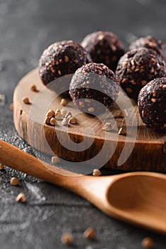 Raw vegan snack. Homemade energy bites made of green buckwheat, nuts and dried fruits on wood slab with wooden spoon