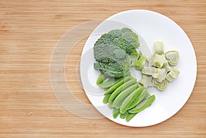 Raw of vegetables baby food broccoli and sweet pea in white plate with frozen mashed baby food homemade in white ceramic bowl on