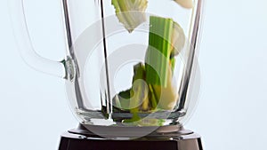 Raw vegetables blender bowl on white background close up. Vitamin cocktail.