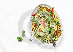 Raw vegetables slaw salad on light background, top view. Zucchini, bell peppers, carrots, squash, green peas salad.