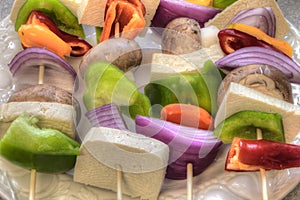 Raw Vegetables and Tofu are prepared for Kabobs on a Cutting Board