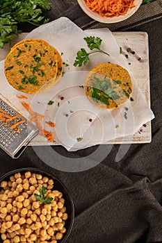 Raw veggie burger with chickpeas vegetables and parsley leaves on kitchen countertop