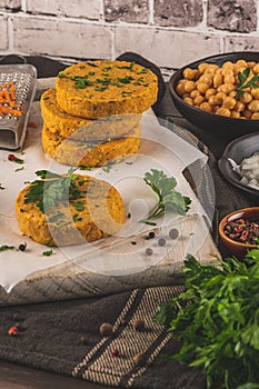 Raw veggie burger with chickpeas, vegetables and parsley leaves on kitchen countertop