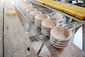 Raw vintage style kaolin cups or China clay cups are arranged in rows on the shelf.