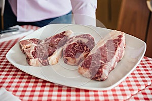 Raw wagyu beef cuts from left to right: T-Bone Steak, Rib Eye and Boneless Top Loin Steak.