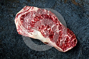 Raw Wagyu beef striploin steak on stone table.