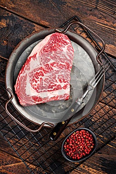Raw wagyu rib eye beef meat steak in steel tray. Wooden background. Top view