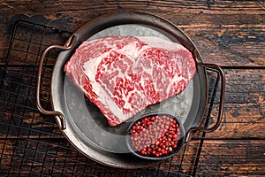 Raw wagyu rib eye beef meat steak in steel tray. Wooden background. Top view photo
