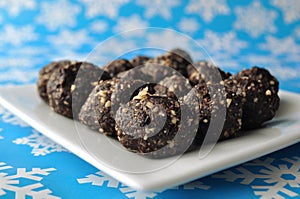 Raw walnut, chocolate and date balls on a white plate and winter background with snowflakes