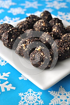 Raw walnut, chocolate and date balls on a white plate and winter background with snowflakes