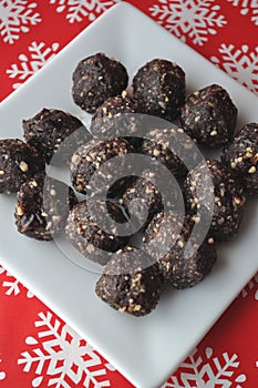 Raw walnut, chocolate and date balls on a white plate and winter background with snowflakes