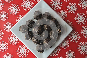 Raw walnut, chocolate and date balls on a white plate and winter background with snowflakes