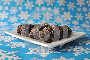 Raw walnut, chocolate and date balls on a white plate and winter background with snowflakes