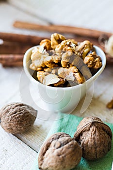 Raw walnuts in a white bowl, white background