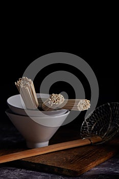 Raw wheat udon noodles in asian style ceramic bowl, Oriental and Asian cuisine, dark key