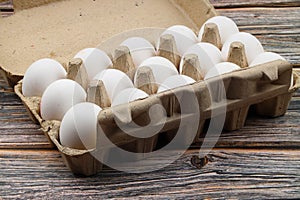 Raw White Eggs in a paper box on a black background, top view. Copy Space for text