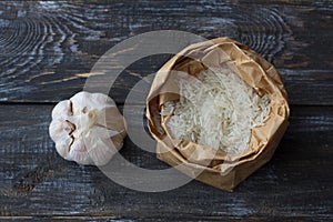 Raw white long-grain basmati rice in a craft bag with garlic on a wooden table