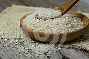 Raw white rice Thai Jasmine rice in brown bowl and and ear of rice or unmilled rice on wooden background