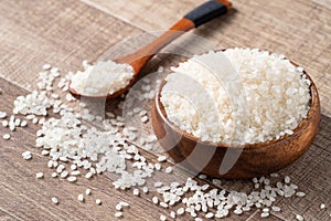 Raw white rice in a wooden bowl over table