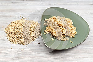 Raw whole oat grains and boiled porridge on plate