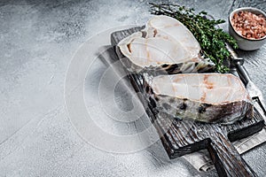 Raw wolffish fillet fish Steak on wooden cutting board. White background. Top view. Copy space photo
