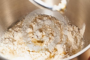 Raw yeast dough mixing in large metal bowl in mixer. Flour, water and yeast mixing