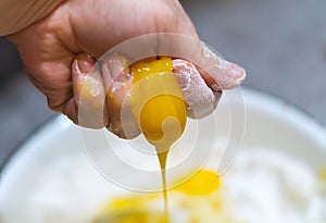 The raw yellow egg yolk is rubbed in the hand and runs down the finger. Manual pressing of a fresh chicken egg. A woman crushes an
