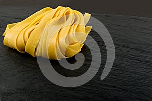 Raw yellow italian pasta fettuccine, fettuccelle or tagliatelle