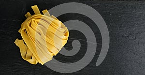 Raw yellow italian pasta fettuccine, fettuccelle or tagliatelle