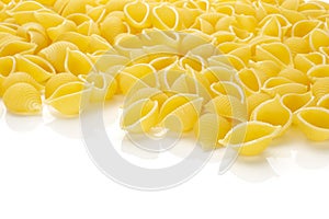 Raw yellow pasta conchiglie isolated on white