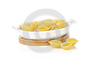 Raw yellow pasta conchiglie isolated on white