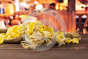 Raw yellow pasta conchiglie with rustic kitchen