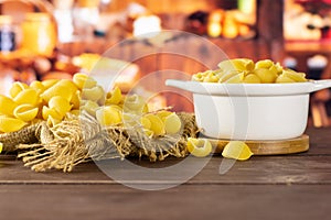 Raw yellow pasta conchiglie with rustic kitchen