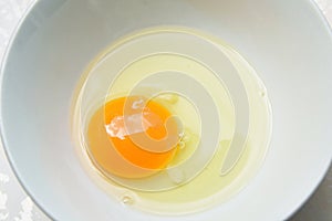 Raw yolk and white egg cracked from shell in cup