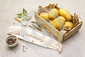 Raw young potatoes and frozen hake fillets. Ingredients for fish and chips. Spices and herbs on a stone background