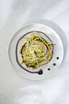 Raw zucchini noodles in on the plate close up