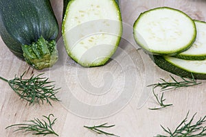 Raw zucchini in pieces with fennel on wooden background