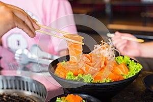 Raws salmon fillet with chopsticks on dish in restaurant