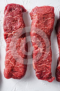 Rawset of denver steak for BBQ  cut organic meat cut top view close up over white concrete background vertical