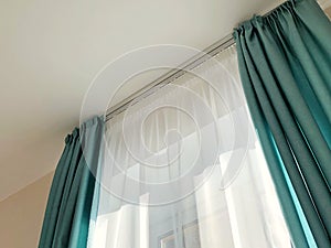 ray of sun lighting through transparent curtain on window into bedroom