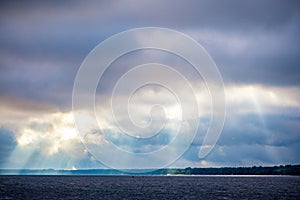 The rays of God in the river landscape. The sun's rays shine through the clouds over the water surface and the shore