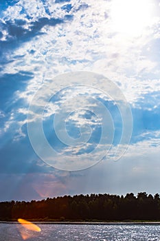 The rays of God in the river landscape. The sun`s rays shine through the clouds over the water surface and the shore. Copy space